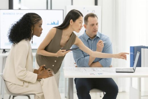 A diverse team of professionals collaborating around analytics charts and a laptop during a data strategy discussion.