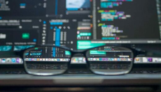Close-up of a pair of glasses in front of a laptop screen displaying data and code, symbolizing clarity and focus in data capabilities.